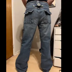 unika raka/baggy jeans med coola fickor och ett spänne på baksidan för att justera midjan!   -midjemått rakt över= 46cm -innerbenslängd= 80 cm -Längd på hela= 106 cm 