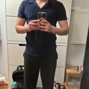 Marinblå piké i frottématerial slim fit - Marinblå pikétröja i frotté material skick  9/10 låg användning, inga skador på plagget. Säljer plagget för att jag inte använder det.