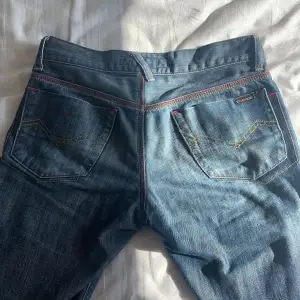 supersöta low-waisted blå jeans med små röda detaljer. köpt i England, made i Italia. har små revor på baksidan av anklarna men märks knappt. midjebandet är 38/39 cm när det är platt. passar bra mig som är 169