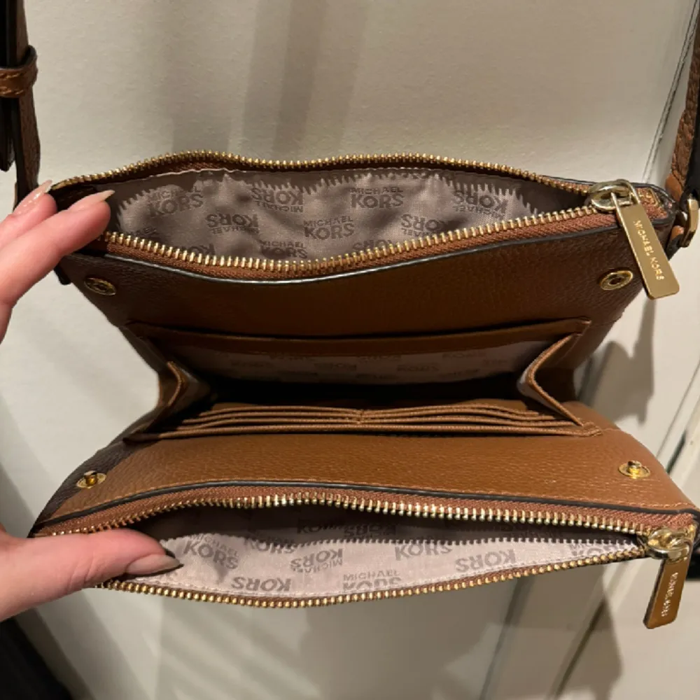 Brun Michael Kors crosdbody väska med double zip och kortförvaring i mitten. Använd fåtal gånger och inga fläckar inuti. Material är “pebbled leather”. Skriv för fler bilder, har bild på authenticity tag också. Säljer för 750kr eller bud.. Accessoarer.