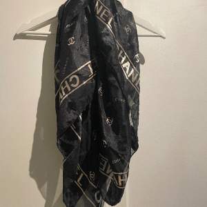Second hand scarf med Chanel tryck i svart och guld. Finns slitningar se sista bilden. Använt som scarf/topp/utsmyckad på väska etc. 