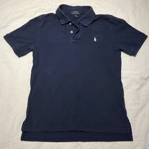 Ralph Lauren pikétröja  - Blå Ralph Lauren pikétröja i fint men använt skick, tröjan är slim och passar därför förmodligen inte lite större personer. Annars passar den personer som är 165-175 cm långa. Nypris på tröjan är cirka 900 kr. 