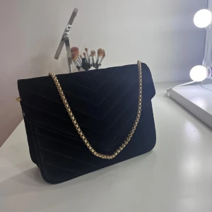 Väska - Säljer en axelremsväska med guldigkedja. Oanvänd och går att låta kedjan vara lång eller kort för att ha som en baguetteväska. 