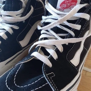 VANS “OFF THE WALL” Sneakers - Ett par stilrena och bekväma VANS “OFF THE WALL” sneakers i storlek 38. Perfekt för dig som söker kvalitetsskor till ett förmånligt pris! Skorna är svarta med vita snören och detaljer, samt den ikoniska röda VANS-logotypen på tungan.