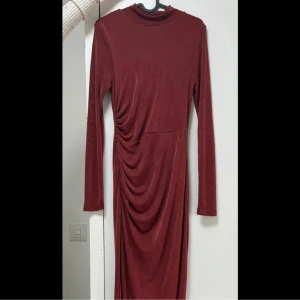 Långklänning - oanvänd - Oanvänd klänning från fashionnova köpt för 499kr. Passar för alla som har mellan storlek xs, s, m.  Oanvänd, endast testad. Kommer ner till hälarna, sitter som ett smäck. Har en stretchig material. Färgen är bronze/röd. Priset kan alltid diskuteras☺️🙏🏼