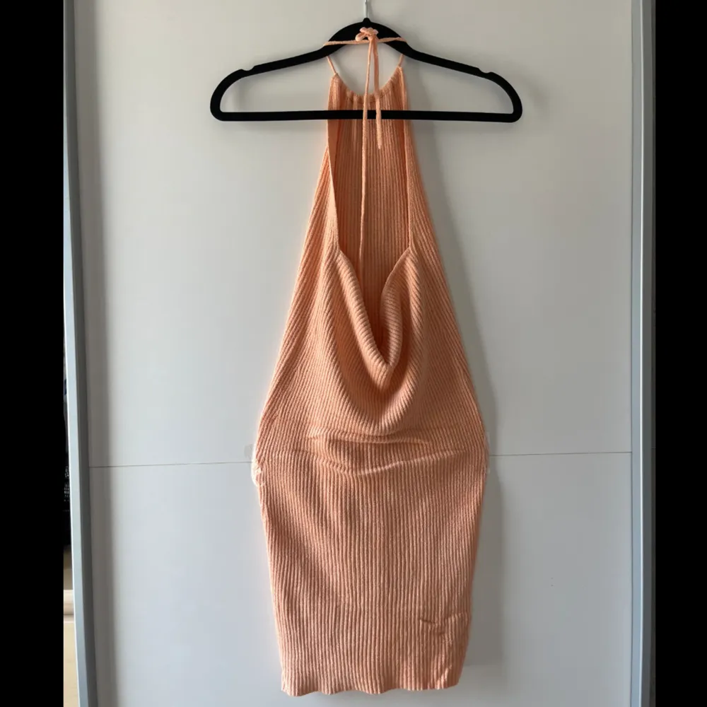 Pastell orange Bershka haltnerneck mini klänning, köpt sommaren 2023. Jag har använt den 2 gånger och den är i jätte bra skick. Stickat men tunt material, ej för varm att ha på sommaren. Obs. Kan tvättas och strykas om önskas🤗. Klänningar.
