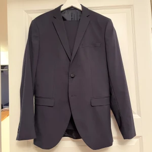 Kostym - Mörkblå kostym från Selected Homme. Kavaj i storlek 46 och kostymbyxor i storlek 50. Använd endast ett fåtal gånger.