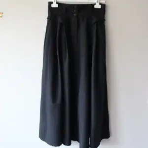 Svart finare kjol med två fickor fram, gjord och från Storbritannien, inget märke. Storlek 38. Knappt använd! Längd: 93 cm, midja (tvärs över) ca 36 x 2