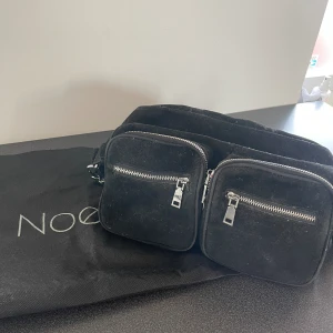 Noella Väska - Svart noella väska i den stora modellen. Kort samt långt band finns till samt dustbag medföljer. Finns många olika fickor och fack. Använt en del så dragkedjan är lite slapp men annars är allt bra🩷