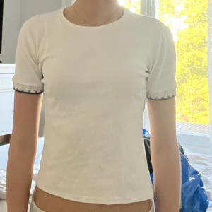 Tshirt med broderad kant - T-shirt med broderad mudd på armen. 