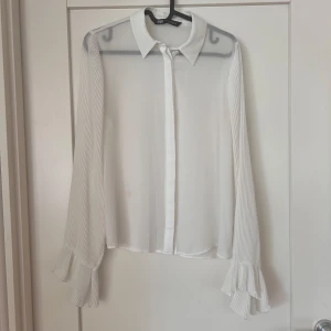 ZARA blus med volang - Lätt transparent vit blus från ZARA. Plisserade armar med volang.  Strl. M (passar en S-M)