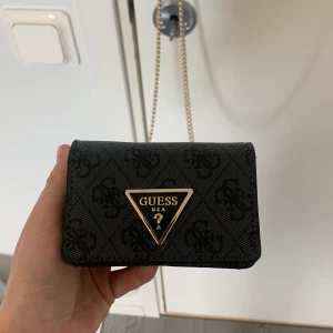 Ny guess väska  - Fin äkta Guess väska i nyskick, använd fåtal gånger. Finns inte att köpa längre men köpt för 1200 kronor. Inga tecken på användning över huvud taget, utan ser helt ny ut. Hör av dig vid frågor så svarar jag så fort jag har möjlighet!💗