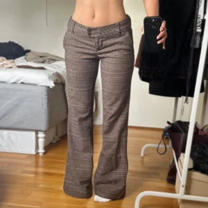 Lågmidjade bootcut kostymbyxor  - Sjukt snygga bootcut kostymbyxor med brunt rutigt mönster. Säljer då dem är lite långa på mig som är 157cm (står på tå på bilden). Byxorna har inga synliga skador och är av god kvalite. 