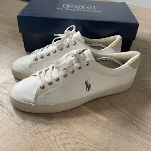 Vita sneakers från Polo Ralph Lauren - Säljer ett par vita sneakers från Polo Ralph Lauren. Skorna är i bra skick och har en klassisk design med snörning och Polo-loggan på sidan. De är tillverkade i skinn och har en bekväm passform. Perfekta för vardagsbruk! Ny pris 1500