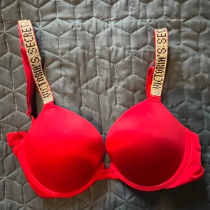 Victoria’s Secret push-up BH - En röd Victoria’s Secret push-up BH i storlek 32D/70D. BH:n har glittriga band och är oanvänd. 