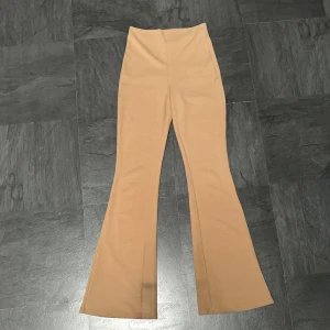 Beige vida byxor - Säljer ett par beige byxor med hög midja. Byxorna är vida och har en skön passform. Perfekta för både vardag och fest! De har en svart fläck på ena benet från skor, därav priset. Storlek Xs