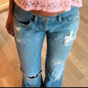 Blå slitna jeans - Säljer ett par blå jeans med slitningar. De är lågmidjade och är utsvängda dem är fint skick och säljer då dem var för stor för mig som vanligtvis har xs i jeans  jag skulle säga att dem passar s-m Midjemåttet är 40cm tvärsöver!!