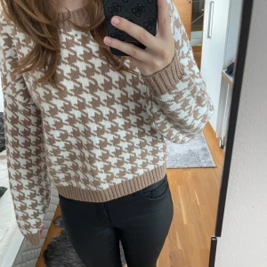 Brun och vit stickad tröja - Säljer denna supermysiga stickade tröjan i brunt och vitt hundtandsmönster. Tröjan är från Hollister i storlek S och knappt använd. Perfekt nu för kommande höst och vinter! 🧡