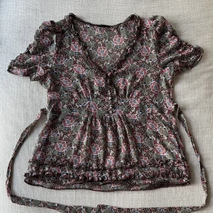 Stockholm LM Blus - En jättegullig blus från Stockholm LM som aldrig är använd. Skicket är 10/10 utan defekter! Finns band som ska knytas i ryggen som ger en snygg passform och ärmarna är lite puffiga. Står 42 men mer som 38 eller 40 (M). Skriv gärna om ni har några frågor!!