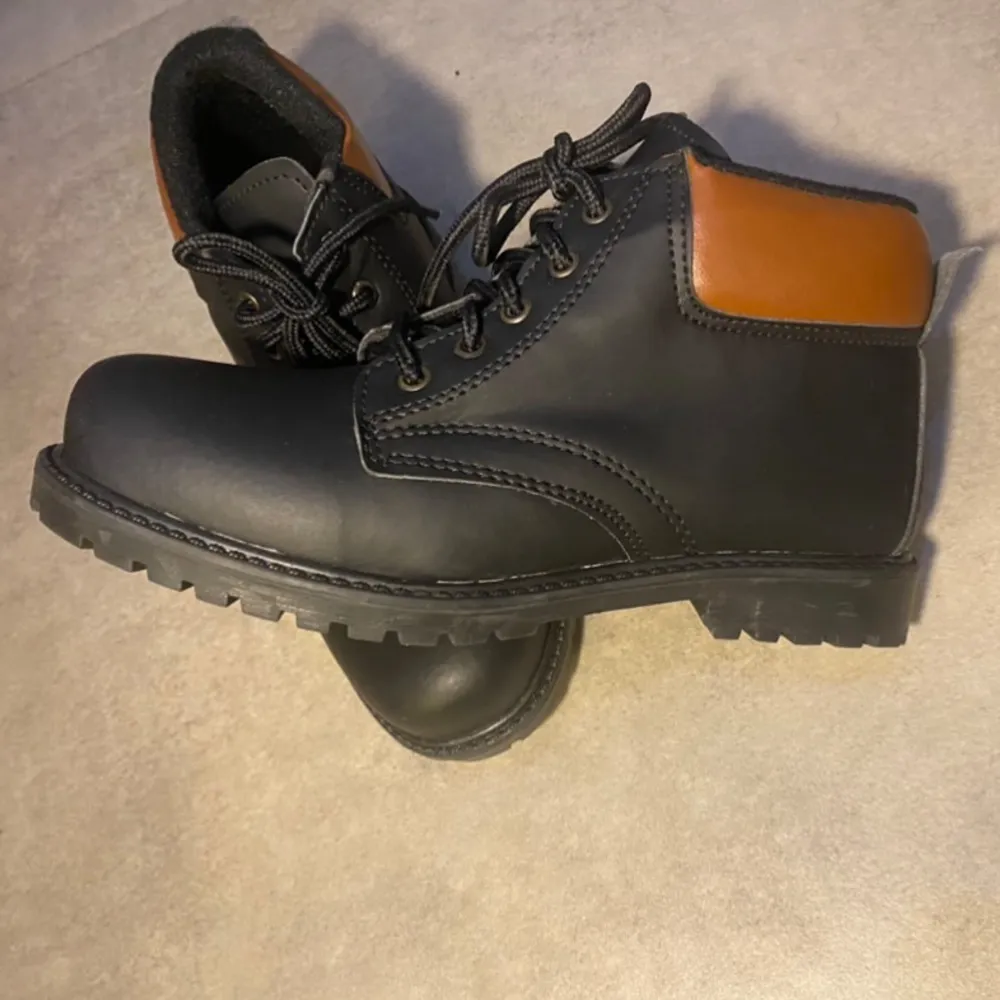 Svarta boots med bruna detalje på utsidan. Helt ny och oanvänd dock utan prislapp . Skor.