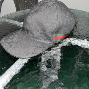 Svart Gucci keps(äkta) - Säljer en svart Gucci keps i storlek S Den är äkta !Liten skada på knappen som ligger på toppen av kepsen som man kan se på sista bilden! !Fraktar endast! Kan sänka priset vid snabb affär