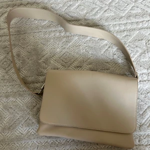 Vit -beige ”läder” väska  - Jättefin ”läderväska” köpt för ca 2 år sedan från Nelly. Använd ca 3-4 gånger men som ny.   Köpt för ca 300kr. 