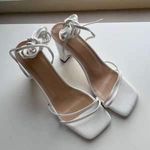 Vita klackskor - Vita klackar i nyskick. Endast testade. Storlek 40 med 9 cm klack och 90 cm långa band som man kan knyta hur man vill. 