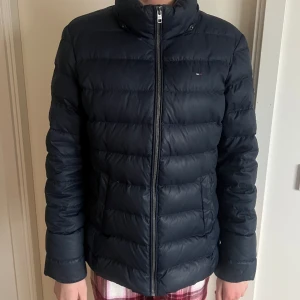 Tommy Hilfiger jacka  - Marinblå dunjacka från Tommy hilfiger, väl använd men fortfarande bra skick, storlek XL (barn) skulle säga att den är en S/M i storlek, luvan är avtagen (och bortappaf tyvärr men funkar prima utan) 