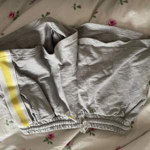 Ett par gråa mjukis shorts med gula detaljer, lite sönder vid ena snöret