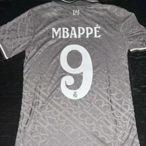 Mbappe Real Madrid tröja - En fantastiskt fin Mbappe Real Madrid 3rd kit tröja, säsong 2024/25. Helt ny och oanvänd. Tröjan är player version, och har UCL patch på ärmen.   Storlek: S