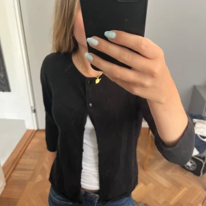 Svart trekvarts armad kofta  - En svart trekvartslång tröja med knappar hela vägen ner kommer från hm 