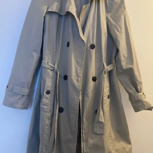 Kappa beige - Jätte stilren kappa. Beige färg. Med bälte och adjustment straps på armarna.