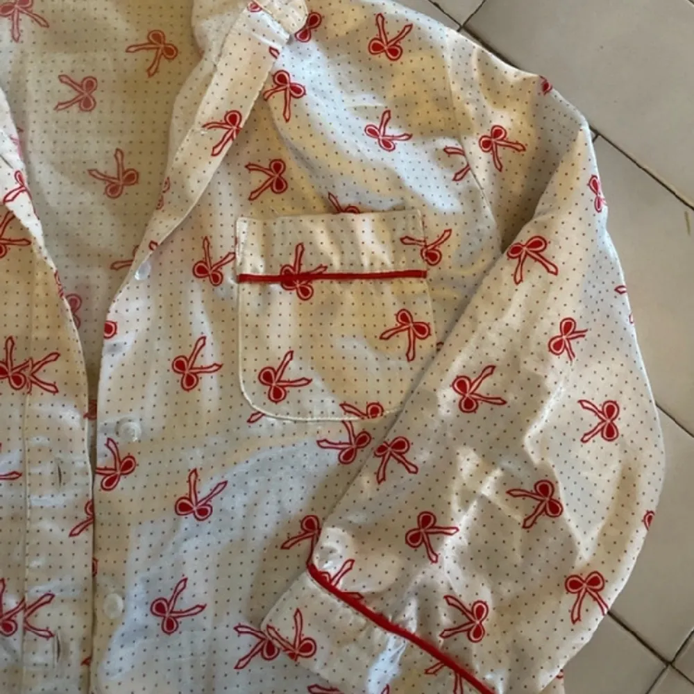 Extremt söt pyjamas överdel - skjorta med röda rosetter. Materialet är tunnare och är av polyester så den är väldigt mjuk och len! Det står att storleken ör 134/140 men skulle säga att den passar som en XS                        Skriv priv för frågor. Blusar.
