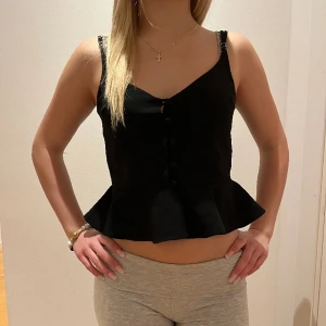 Svart volangig topp - Säljer min svarta, volangig topp med små knappar som inte kommer till användning 💗superfin till fest/sommaren osv. 