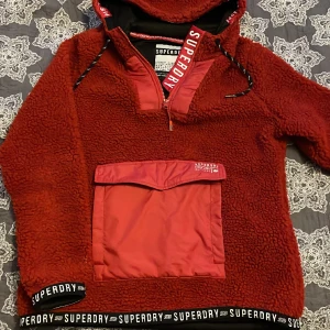 SUPERDRY - Superdry ”storm jacket”, med ficka på magen, huva med dragkedja. Väldigt skön och varm, skick 10/10.  Aldrig använd