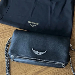 Zadig väska - Säljer ju min zadig väska som är använd 2 ggr💕 Helt ny och knappt använd så skicket är jättebra. Köpt i zadig butiken i sthlm. Det är den nyare modellen så man kan byta ut vingarna i olika färger💘 nypris ca 4100, det är mellan strl priset är diskuterbart❣️