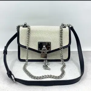 Framed black piping and accented with polished hardware, this unique shoulder bag is a perfect addition to your closet. The perforated finish and the adjustable strap offers a lightweight option that boasts endless styling opportunities; Logo plate at fro