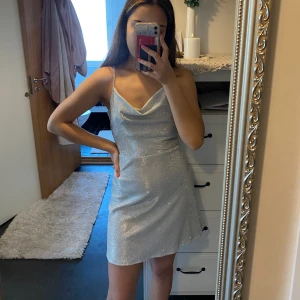 Glittrig klänning  - Jättefin grå glittrig klänning från Hm som aldrig använts och är i helt nyskick. Strl S. Kan spännas på ryggen och anpassas till personen.