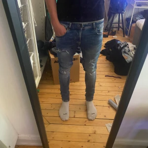 Mörkblå jeans - Mörkblå jeans med slitage. Modellen är slim fit storlek 30/32. Modellen på bilderna är 185cm och ca 70kg. 