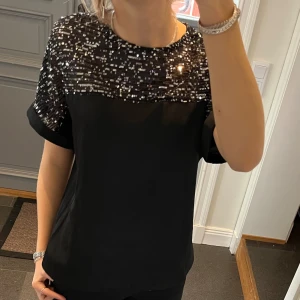 Svart paljettröja  - Svart tröja med paljetter från Dorothy Perkins i storlek 38. Fint skick. Använd gärna köp nu!