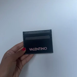 Svart Valentino korthållare  - Använts några gånger. Har några repningsr på baksidan men inget man tänker på! Skriven i vitt med 3D färgat i rött.  Perfekt present till kille, bror eller pappa! Ursprungspris: 450kr