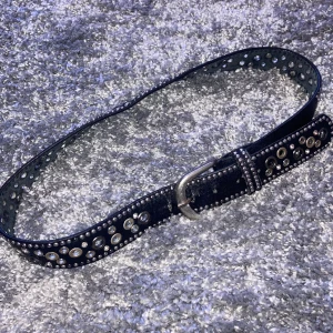 Rhinestone/Nitbälte - Ett jätte coolt svart läderbälte med rhinestones, runda nitar och hål i sig. Får tyvärr inte mycket användning av mig själv längre. Bra läder kvalitet. 85cm