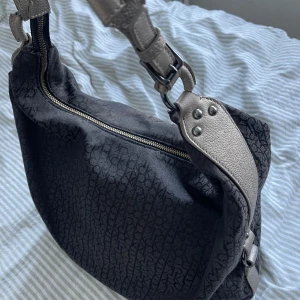 Calvin Klein Väska - Calvin Klein väska, köpt second hand så vet ej om den är äkta men är i nytt skick, då den var inplastad vid köp och knappt använd av mig! Rymlig och unik! Pris är diskuterar vid snabb affär!
