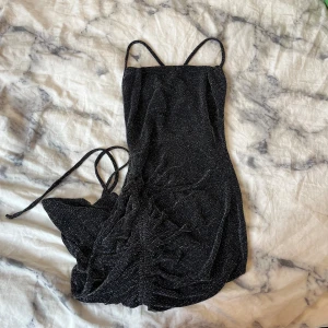 Glittrig klänning - Jättefin klänning från Nelly med öppen rygg. Endast använd en gång. Glittrar jättemycket och ser jättefin ut på.