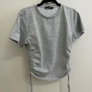 Jättefin grå T-shirt med dragsko på sidan. Knappt använd. 
