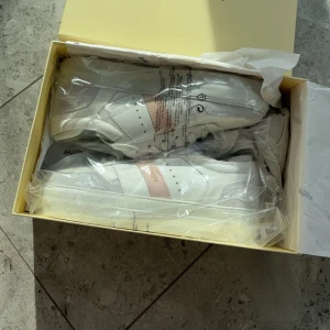 Helt nya AXEL ARIGATO - Hej!  Säljer mina helt nya Arigato-sneakers i storlek 37 för 1000 kr. De är oanvända och super fina. Det är rosa samt grå/blå detaljer.