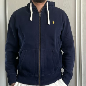 Ralph Lauren hoodie - Mörkblå luvtröja från Ralph Lauren med gul häst. Använd men i bra skick. 