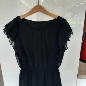 Klänning  - Svart kläning med volang i bra skick 