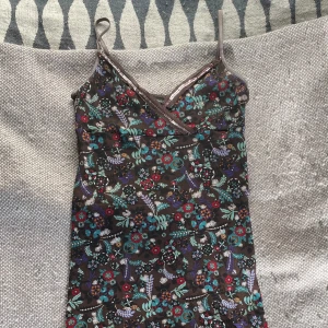 Klänning - Söt brun mönstrad klänning med justerbara axelband och paljetter. Något sliten högst upp men inget som är direkt trasigt. Det står XS som storlek men den är stretchig och passar mig som är M.