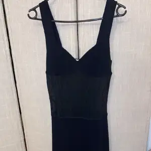 Lång svart klänning som är genomskinlig i midjan